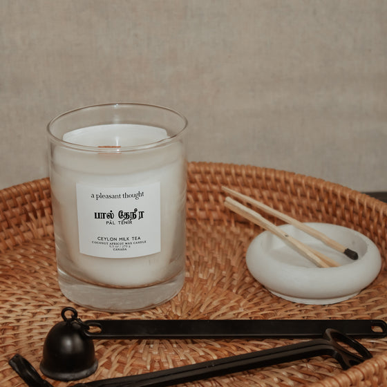 ceylon milk tea inspiration for pal tenir ceylon milk tea coconut apricot wax candle in a classic, clear glass votive with a wooden wick tamil candle displayed