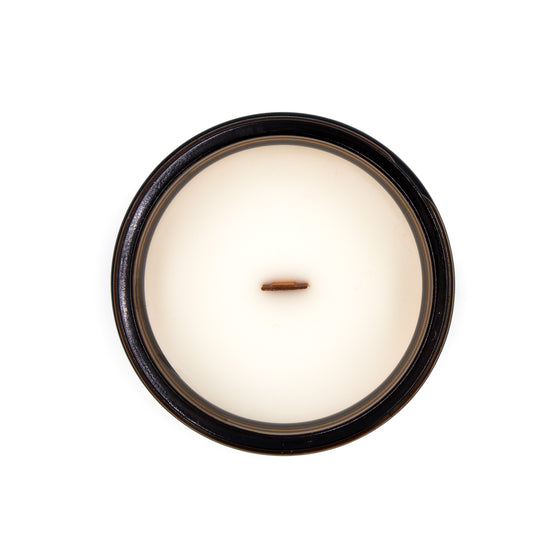 moriarty bergamot and white tea coconut apricot wax candle in a classic, amber glass jar with a wooden wick and lid top