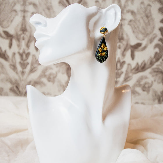Polymer clay earrings black-eyed susan flowers on black teardrop dangles model