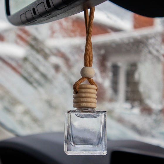 Fragranced car or locker diffuser oil housed in a clear glass cylinder bottle with a wooden top, and cord