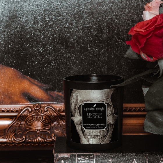 oak whiskey lincoln black coconut apricot wax candle in a matte black glass vessel with a wooden wick a pleasant thought decor