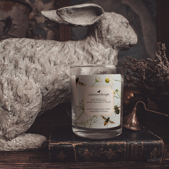 ophelia peach blossom and basil coconut apricot wax candle in a classic, clear glass votive with a wooden wick display