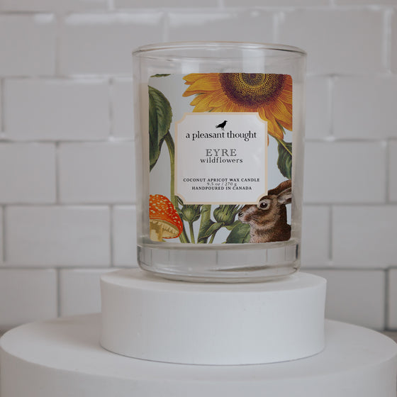 eyre wildflowers coconut apricot wax candle in a clear glass vessel with a wooden wick