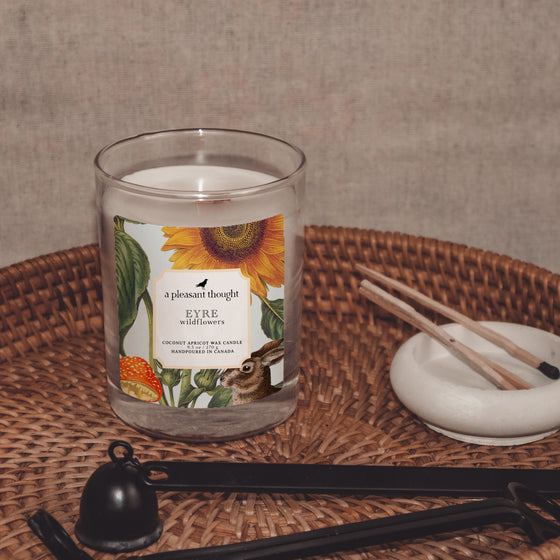 eyre wildflowers coconut apricot wax candle in a clear glass vessel with a wooden wick display