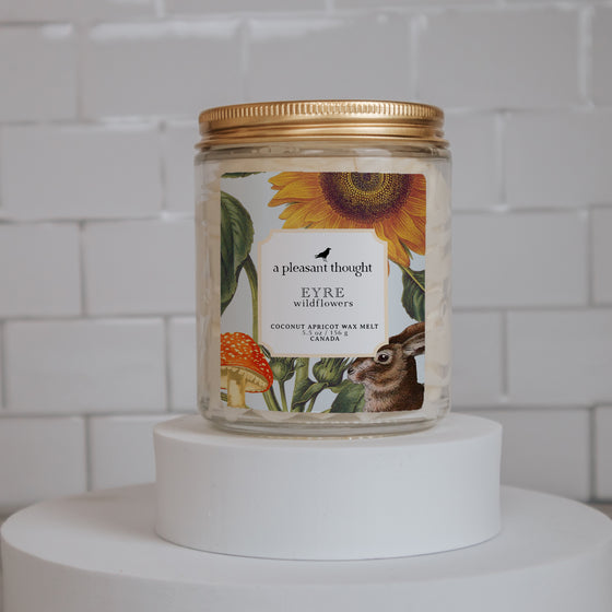 eyre wildflowers Scoopable coconut apricot wax melt whipped into a clear glass jar with a gold lid and spoon