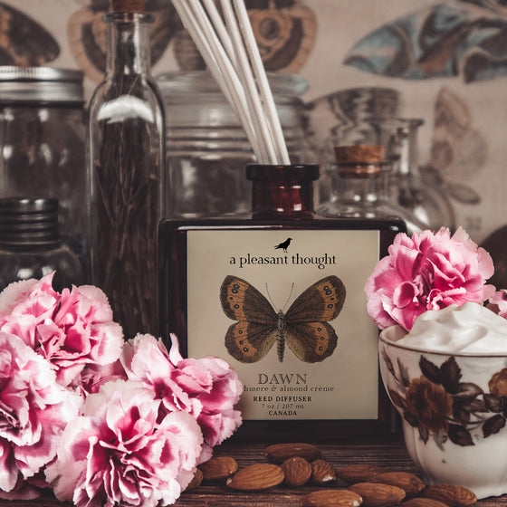 dawn cashmere and almond creme Fragranced diffuser oil housed in an amber glass, apothecary bottle with rattan reeds notes