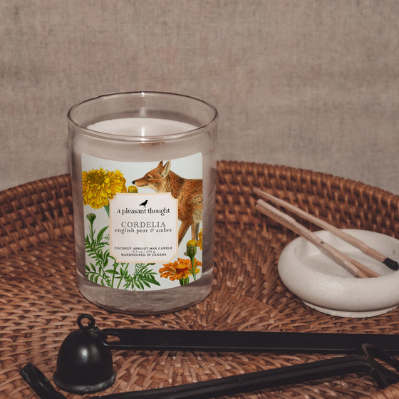 cordelia english pear & amber coconut apricot wax candle in a classic, clear glass votive with a wooden wick display