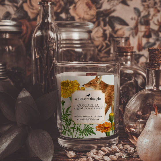 cordelia english pear & amber coconut apricot wax candle in a classic, clear glass votive with a wooden wick notes