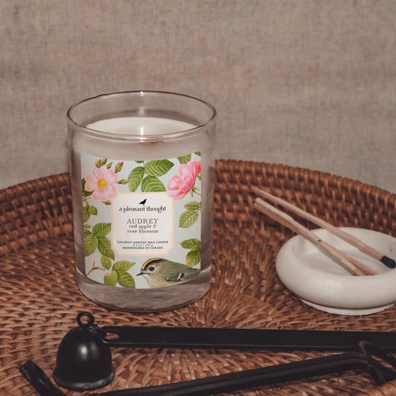 audrey red apple and rose blossom coconut apricot wax candle in a classic, clear glass votive with a wooden wick  display